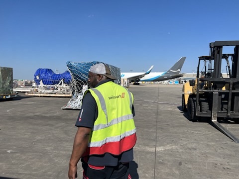 Airport cargo worker receiving protected freight from a forklift