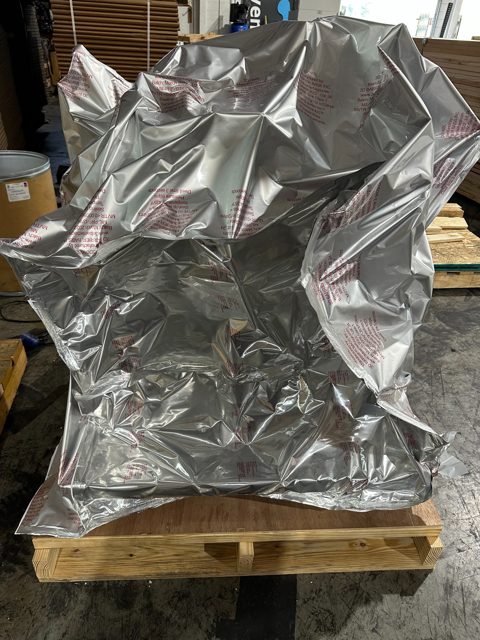 Technician sealing silver barrier film around industrial equipment